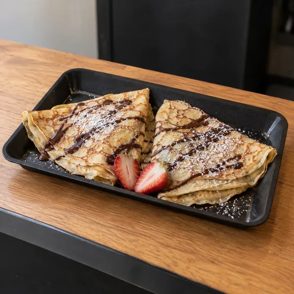 Gefaltete Crêpes mit Schokoladensauce als süßer Serviervorschlag
