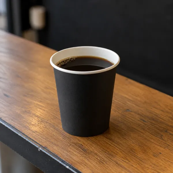 Schwarzer Kaffee in einem dunklen Pappbecher