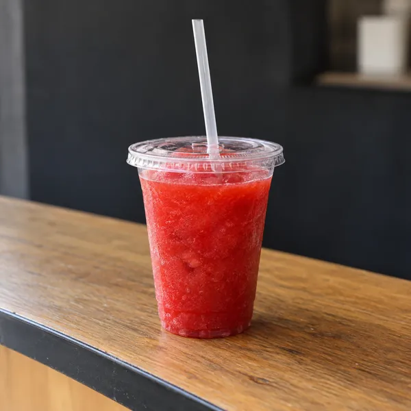 Rotes Slush-Eis im transparenten Becher mit Trinkhalm